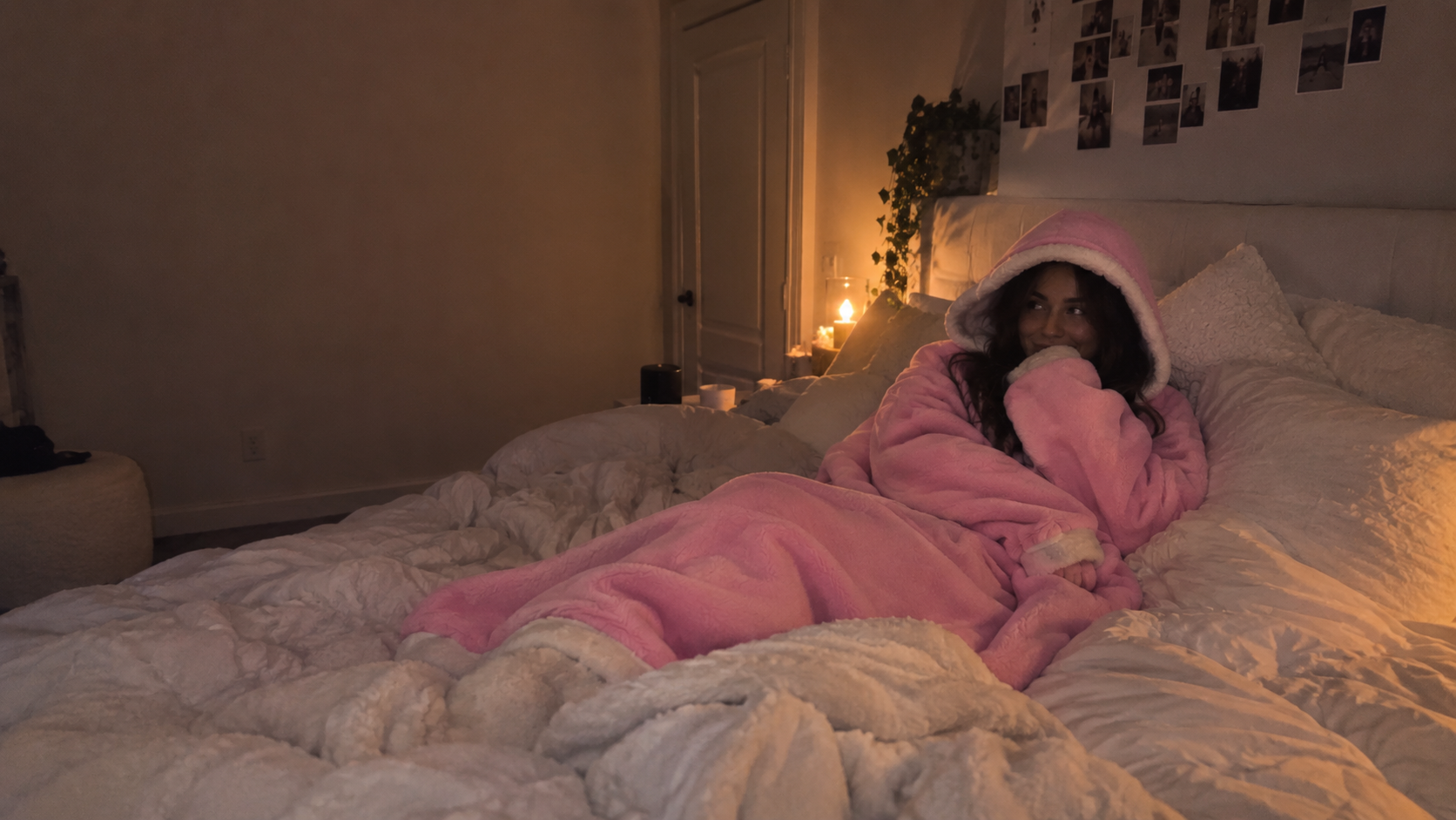 Woman relaxing in a warm bedroom wearing the pink BLANKET HOODIE™